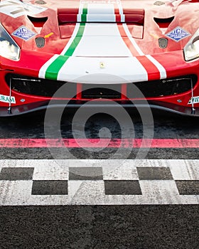 Ferrari racing touring car front detail on asphalt circuit starting line checkered sign marked on motorsport track