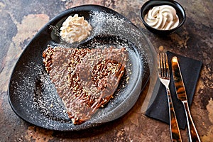 Ferrero Rocher Crepe with hot chocolate, whipped cream, knife and fork served in dish isolated on dark background closeup top view