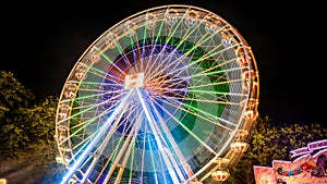 Ferries wheel rotating at night with lights at amusement park