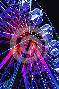 Ferris wheel also known as giant observation wheel, popular entertaining ride in amusement park, night scene low angle view
