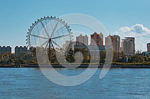 Ferris wheel and amusement park on the Amur River, Heihe city, China. View from the coast of the city of Blagoveshchensk