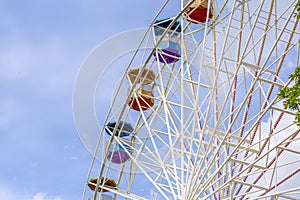 Ferris wheel in amusement Park with clouds and blue sky background.
