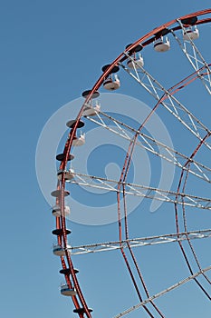 Ferris wheel in the amusement park photographed against the sun. Construction of the attraction with pink sky and clouds