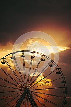 Ferris Wheel in amusement park and scenic sunset clouds in sky and flying birds silhouettes