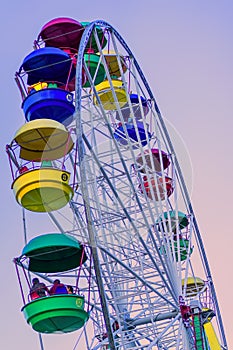 Ferris wheel with brightly colored multicolored cabins against the blue sky