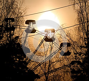 Ferris wheel cabin sunset silhouette surrounded by naked tree branches