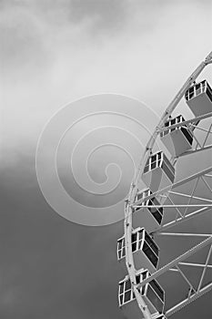 Ferris wheel cars aligned for descent against cloudy sky