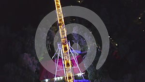 Ferris wheel in a city park at night. Clip. Top view of the glowing Ferris wheel at night