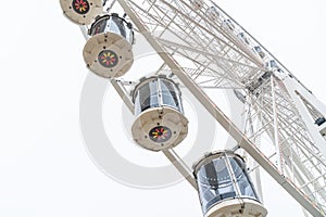 Ferris wheel close-up on gray sky background, traditional fairground attraction