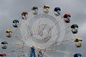 Ferris wheel with colorful booths in the amusement Park on the background of the stormy sky