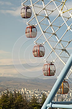 Ferris wheel with colorful cabins against amazing spectacular view of Tbilisi