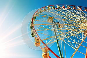 Ferris wheel with colorful cabins against bright blue sunny sky