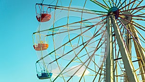 Ferris wheel with colorful cabins on the blue sky background