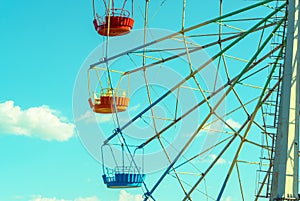 Ferris wheel with colorful cabins on the blue sky background