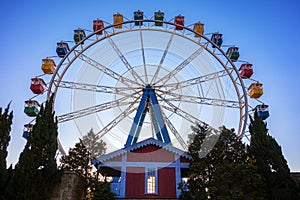 Ferris wheel with colorful swings at sunsets with blue sky in front view