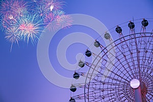 Ferris wheel and fireworks on blue sky