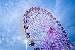 Ferris wheel in front of blue sky with clouds