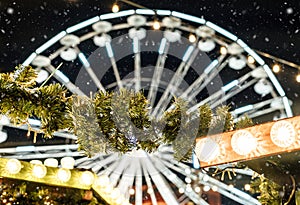 Ferris wheel with garlands at night. Traditional Christmas market decorations in the city. New Year celebration, holidays
