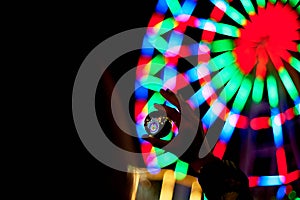 Ferris wheel through a glass ball on the palm of your hand. The atmosphere of celebration and rest. Evening adventure