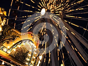 Ferris Wheel and Merry-go-round in an amusement park at night lit up with bright lights