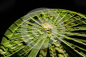 Ferris wheel in motion at the amusement park, night illumination. Long exposure