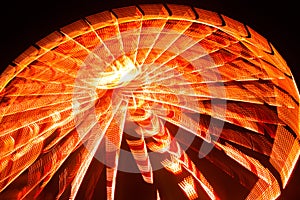 Ferris wheel in motion at the amusement park, night illumination. Long exposure