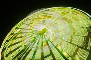 Ferris wheel in motion at the amusement park, night illumination. Long exposure