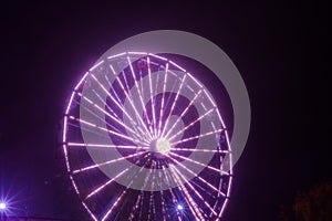 Ferris wheel in motion at the amusement park, night illumination. Long exposure