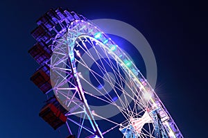 Ferris wheel with multi-colored illumination against the dark bl