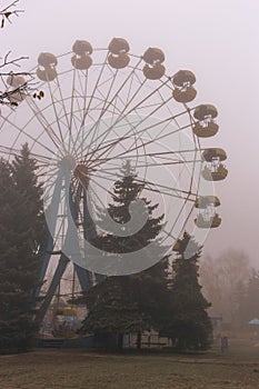 Ferris wheel in an old abandoned park in the autumn in thick fog