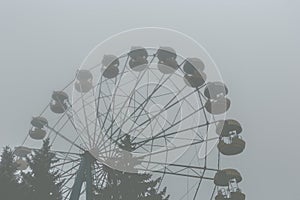 Ferris wheel in an old abandoned park in the autumn in thick fog