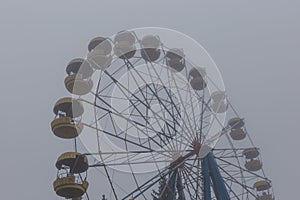 Ferris wheel in an old abandoned park in the autumn in thick fog