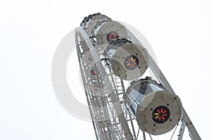 Ferris wheel and row of booths close up on gray sky background