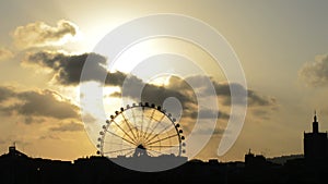 Ferris wheel silhouette spinning at sunset on a cloudy day at timelapse