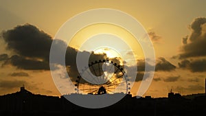 Ferris wheel silhouette spinning at sunset on a cloudy day at timelapse