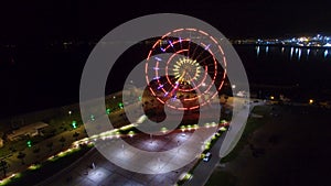 Ferris wheel sparking with lights, Batumi nightscape reflecting in Black sea
