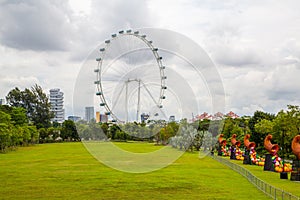 Ferris Wheel surrounded by greenery in the Gardens by the Bay under a cloudy sky in Singapore