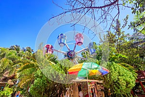 The Ferris wheel, which meets the blue sky, is circling among th