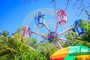 The Ferris wheel, which meets the blue sky, is circling among th