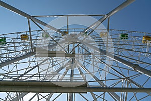 Ferris wheel with yellow and green booths against a blue sky