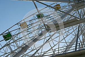 Ferris wheel with yellow and green booths against a blue sky