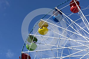 Ferris wheel, yellow, red, blue, green booths, seats, a blue sky