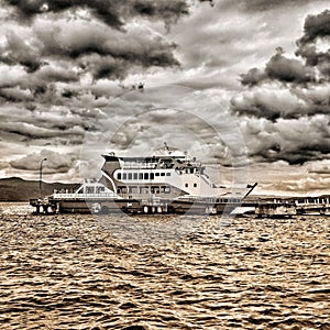 Ferry boat with deep golden water and gloomy sky in Sorowako harbor