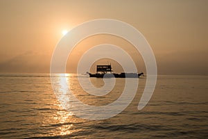 Ferry boat on the Ocean silhouetted against a setting sun and orange sky. Silhouette of the Ferry ship over the sunset Ferry flo