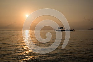 Ferry boat on the Ocean silhouetted against a setting sun and orange sky. Silhouette of the Ferry ship over the sunset Ferry flo