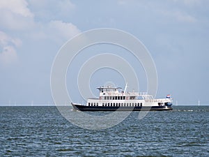 Ferry boat Zuiderzee sailing on lake IJsselmeer and wind generators of windfarm, Netherlands