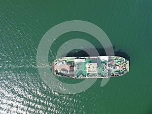 Ferry carrying cars and passengers across the sea, top down aerial drone view. Ferry on the lake, transporting cars