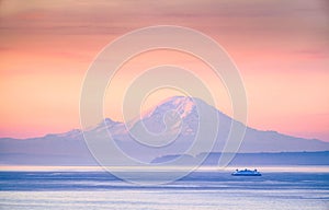 A ferry crossing the Puget Sound at sunrise with Mount Rainier i