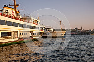 Ferry in Istanbul, Turkey. The Golden Horn at sunset. Yeni Cami mosque silhouette.