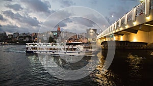 Ferry passing under the Galata bridge at night. Golden Horn. Turkey, Istanbul.